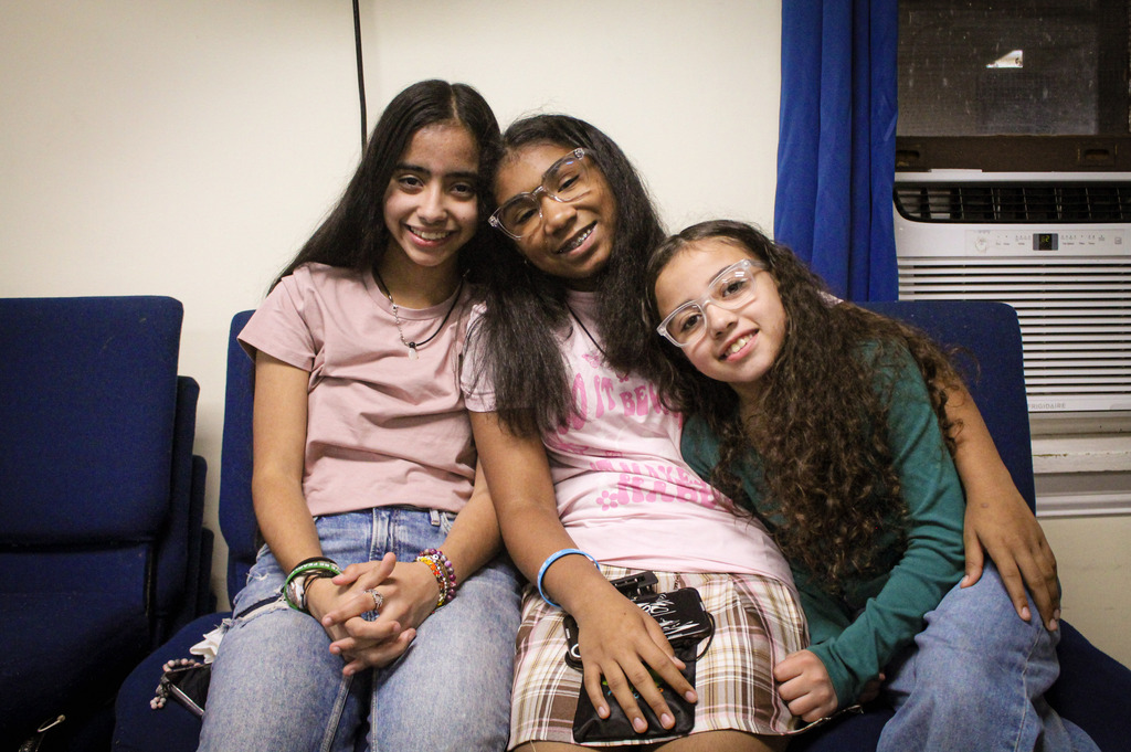 Three girls smiling with heads tilted toward one another