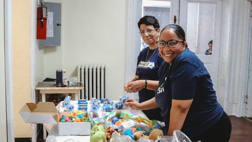 Two volunteers smiling while sorting toys