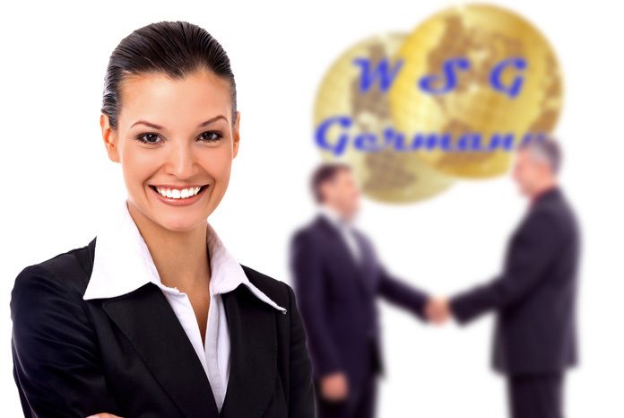 Junge, hübsche, lächelnde Geschäftsfrau im Vordergrund und zwei Geschäftsmänner, die sich vor einem WSG-Germany Logo begrüßen