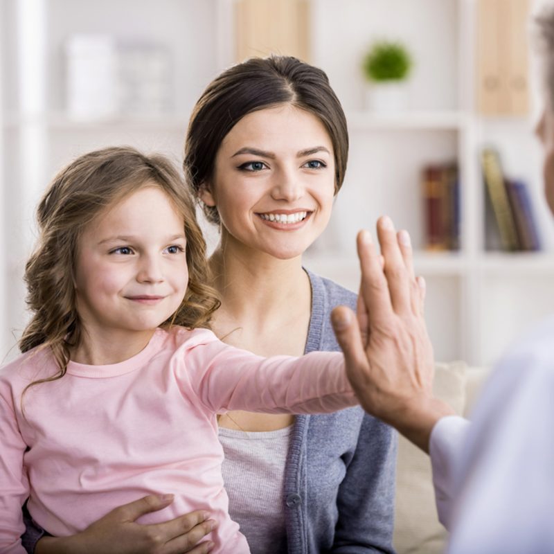 mother and daughter high-fiving doctor